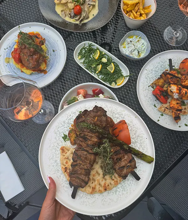 Generous grilled skewers on pita, with charred vegetables and sharing dishes