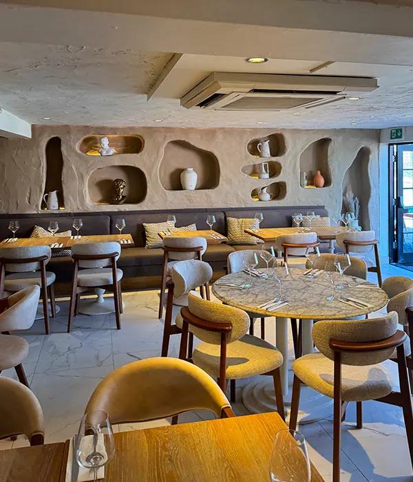 NYXE’s dining room with warm textured walls, curved niches and blue and gold seating