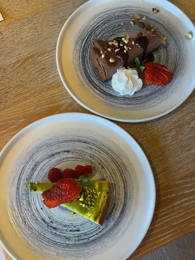 Two NYXE desserts with berries on distinctive textured ceramic plates