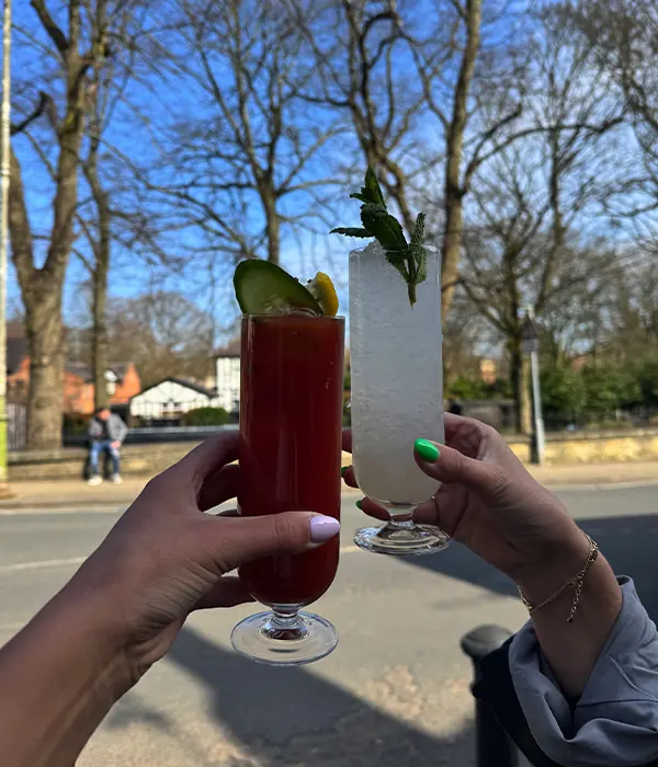 Two people raising NYXE cocktails together outside in Worsley